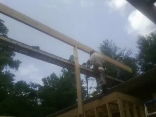 Carpenter setting a ridge beam over a new addition frame — Ice Dam Removal by Roofing Brothers in Gratiot