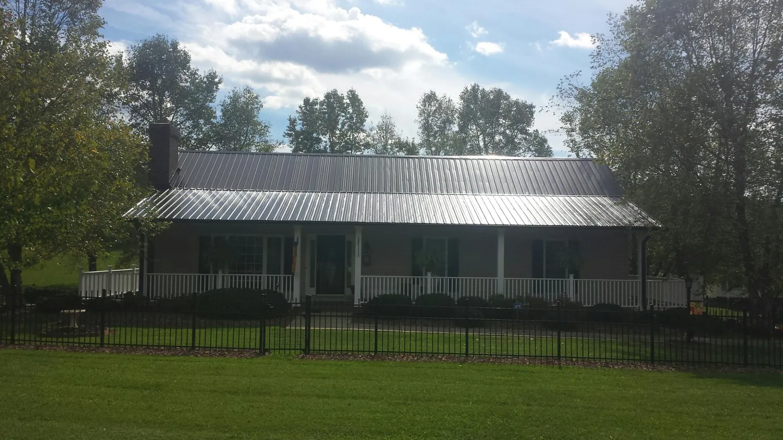 Gray metal roof on a brick ranch with a full width front porch — Gutter Guard Installation work by our crew in Gratiot