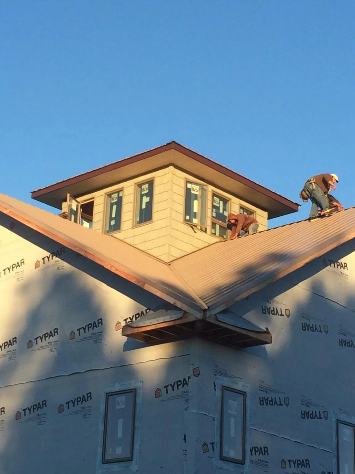 Roofers working around a rooftop cupola on a new metal roof at sunset — Roof Waterproofing in Gratiot by Roofing Brothers